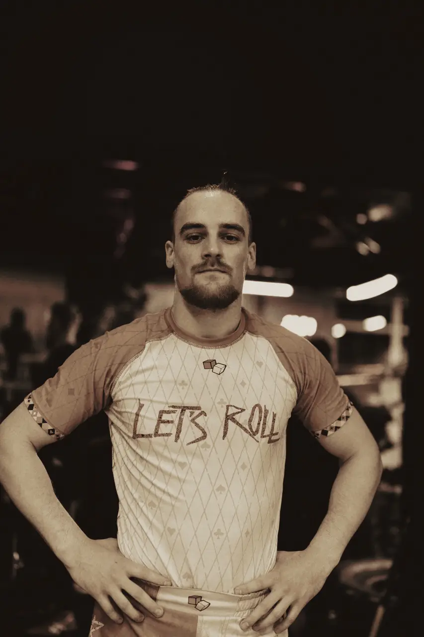Ein Let's-Roll-Athlet trägt den orange-weißen Rashguard in der Halle.