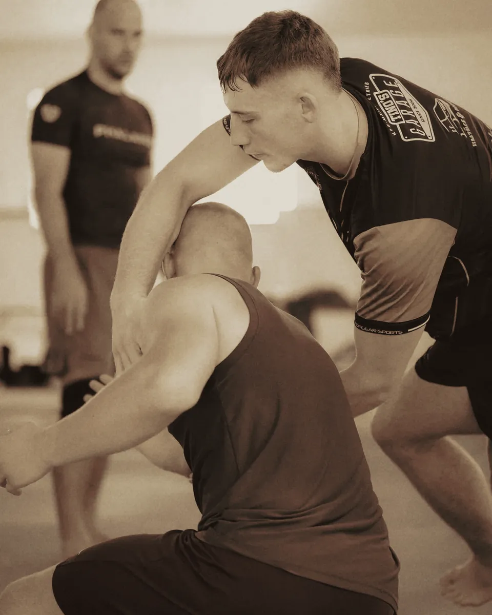 Front-Headlock-Drill, der Coach schaut zu.