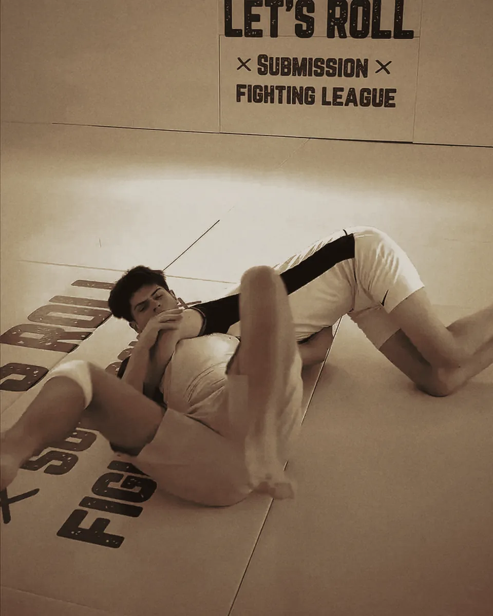 No-Gi-Grappling am Boden vor dem Let's-Roll-Banner.