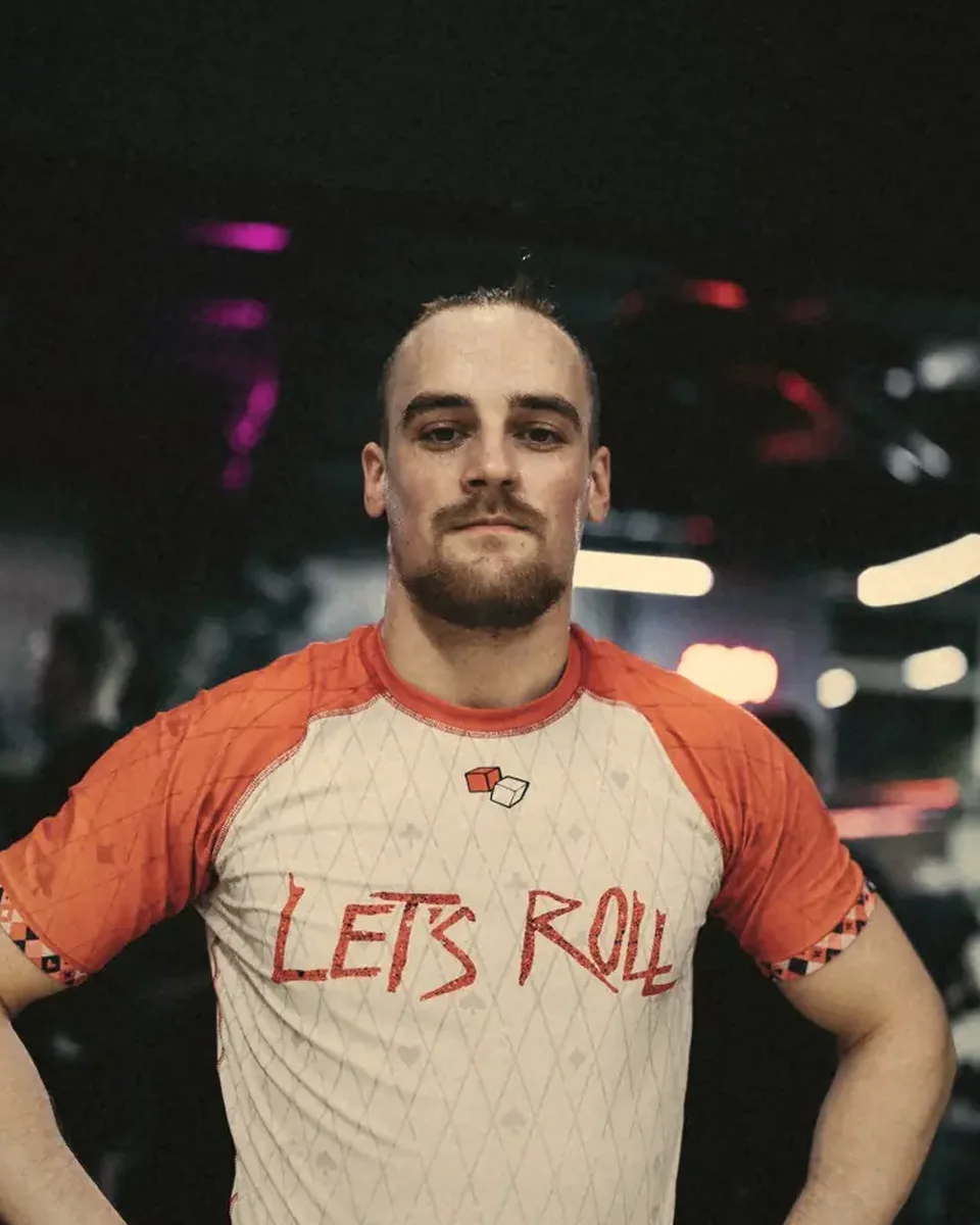 Coach der Let's Roll Academy im Let's-Roll-Rashguard im abgedunkelten Trainingsraum.